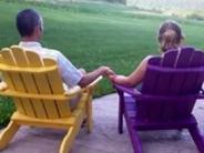 Couple on Adirondack chairs looking out over lawn