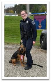Officer Shaylyn Isaacson in uniform with K9 Lucy in a parking lot.