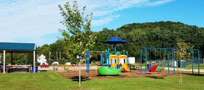 Park with playground equipment and hills and trees in the background Summer day