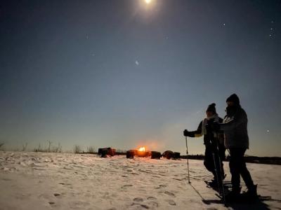 snowshoeing people under the moon walking by the fire